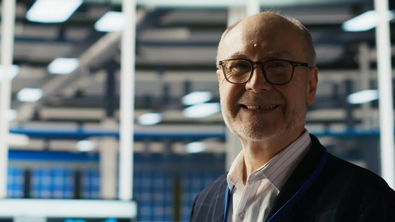 Ein lächelnder Senior-Ingenieur liest in einer Fabrik für Solarpanels Dokumentation.